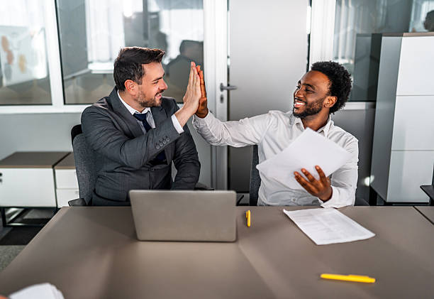 istock Businessmen celebrating achievement with high five in office 2246709420