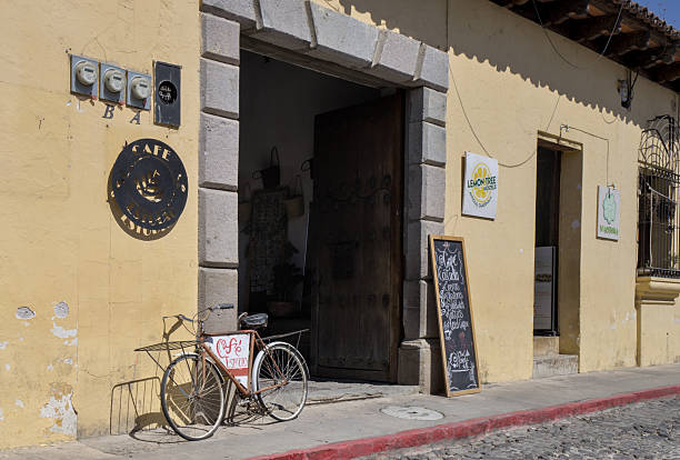 Beautiful colonial building with cafe storefront entrance featuring chalkboard and antique vintage bicycle in Antigua Guatemala, popular travel destination.