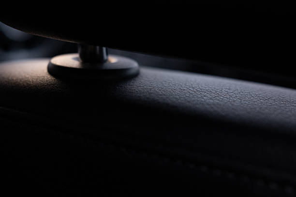 A luxurious close-up of a modern car's black leather interior. Soft light accentuates the fine grain texture of the premium upholstery. Dark, elegant, and abstract background with copy space.