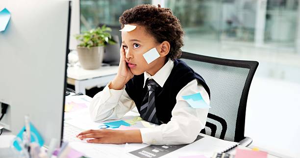 istock Sticky notes, business kid and tired at computer for payroll deadline, crisis management and pretend. Role play, boy child accountant or bored in office for auditing, bookkeeping chaos and overworked 2246715497