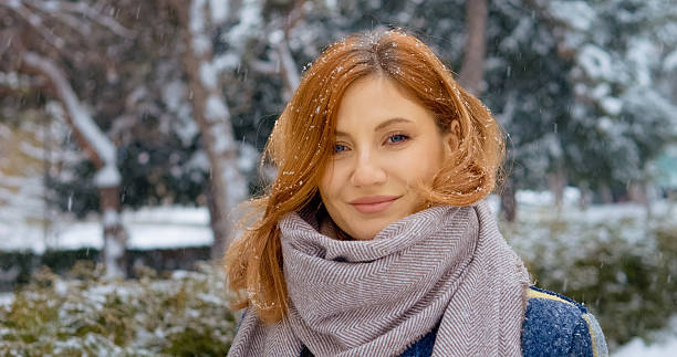 istock Redhead woman enjoys winter snowfall in a serene park setting 2246718891