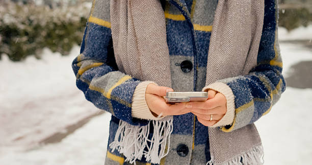 istock Woman enjoying snowfall in park while scrolling on her smartphone 2246720737