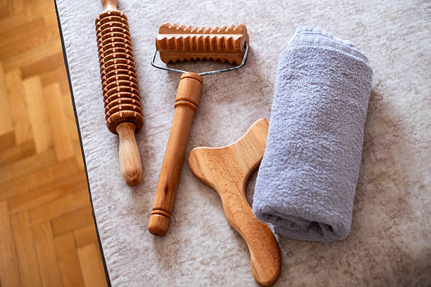 Group of wood therapy tools next to a rolled towel on a massage bed