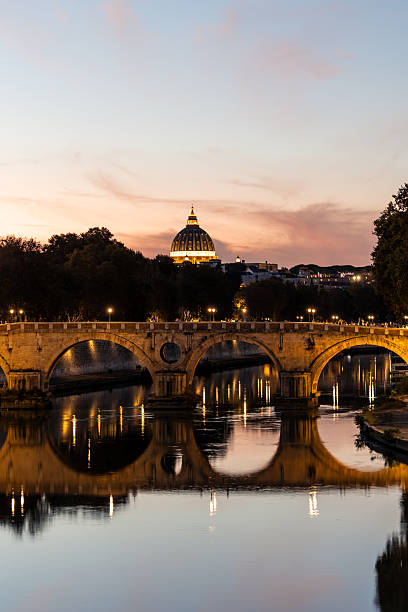 October 10, 2025, Rome. Ponte Sisto lit at dusk, reflecting on the calm Tiber with St. Peter's Basilica dome glowing under an evening sky in Rome, Italy  tranquil historic cityscape and landmark ambiance