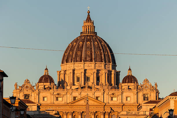 October 10, 2025, Rome. Saint Peter's Basilica dome showcases intricate architecture, illuminated by the warm golden light of a sunset, marking a significant religious and cultural landmark in Vatican City