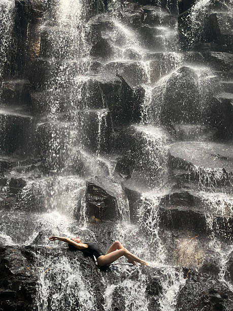istock Woman lying on a stone waterfall. Stretching and doing yoga exercises 2246726390