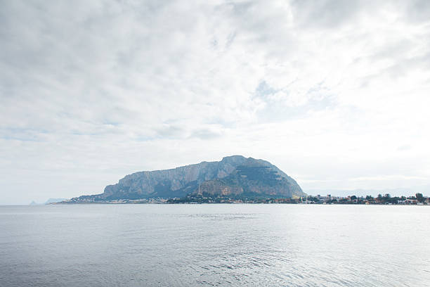 Gentle coastal scene with a distant island mountain, calm water, and a sky filled with soft clouds. Perfect for travel, nature, or peaceful lifestyle visuals.