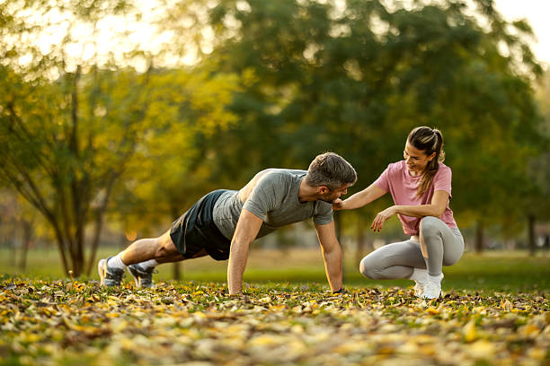 istock Couple exercising outdoors in autumn park with personal trainer 2246734891