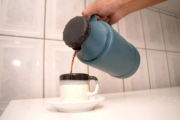istock Pouring Fresh Coffee from Thermos into Ceramic Mug on White Counter 2246736683