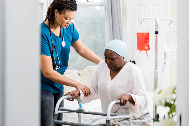 istock Nurse assists elderly patient using a walker with infusion bags in background. 2246737712