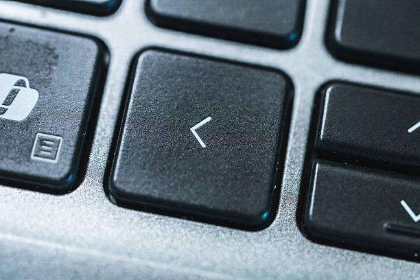 Macro photograph of arrow key on modern computer keyboard with silver metallic frame.
