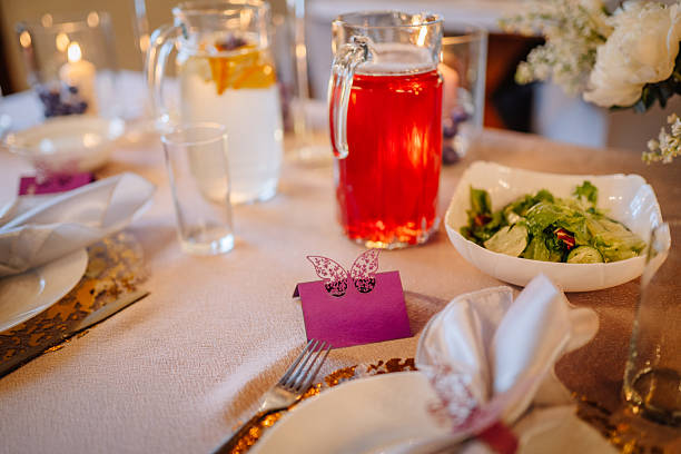 Beautifully arranged dining table for a festive occasion, showcasing vibrant drinks, fresh salad, decorative place cards, and warm ambient lighting enhancing the celebratory mood