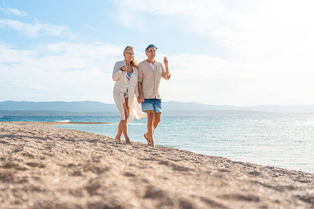 istock Mature Couple Taking Romantic Beach Walk Along Sunlit Mediterranean Shoreline 2246756787