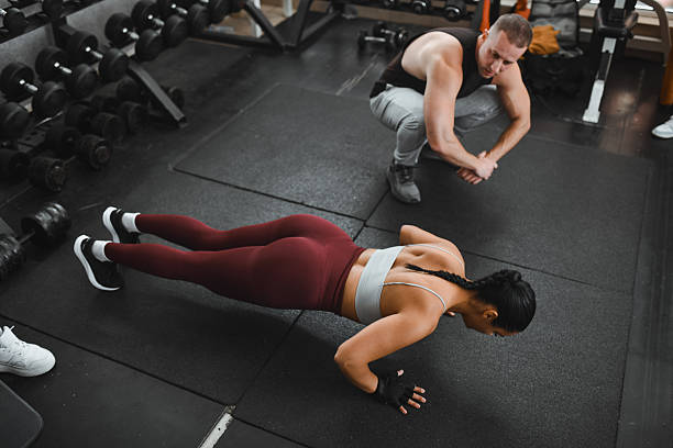 istock Dynamic Gym Workout Scene With Female Athlete Doing Push‑Ups Under Coach Guidance 2246766029