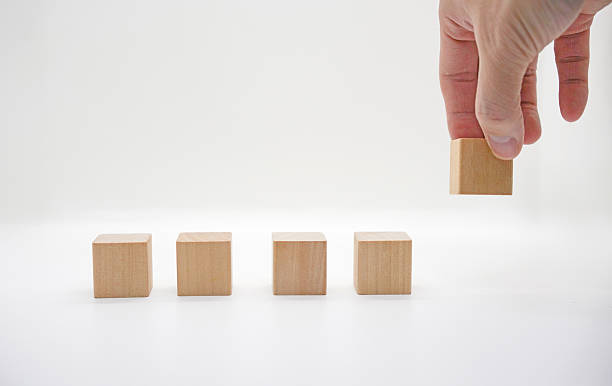 istock Hand Placing Wooden Block on White Background 2246771326