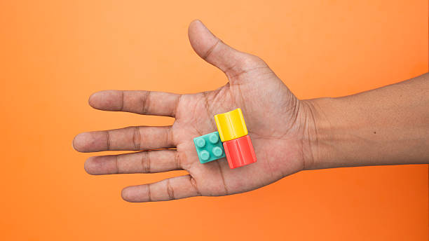 istock Hand gently supports modular construction pieces against orange background. 2246774013