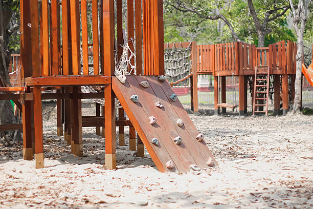 Young boy in green shirt climbing black rope net at playground. Child practicing strength, balance, and coordination while enjoying outdoor activity in park.
