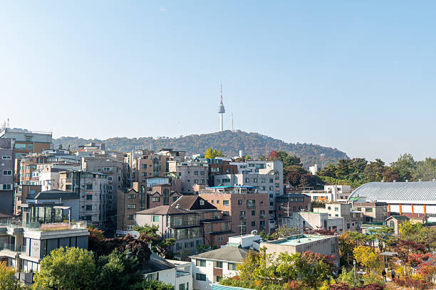 Residential buildings in Seoul on a forested hill during autumn. Urban cityscape with mixed architecture and fall foliage. South Korean city view with skyline and nature.