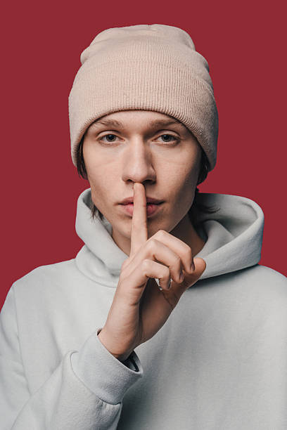 man with cap in studio, intimate podcast setting featuring man in casual attire with quiet demeanor