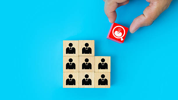 istock Hand choosing people head light bulb on cube wooden toy block stack. Concepts of ideas creative thinking or human resources personnel leader or leadership or business team player performance. 2246778683