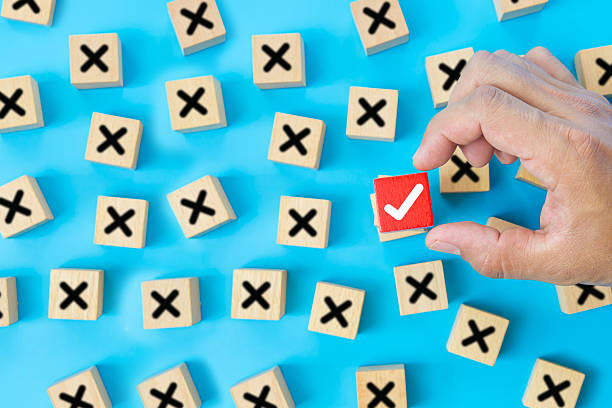 istock Hand choose check mark on cube wooden toy block with cross symbol for true or false changing mindset or way of adapting to change leader and transform quiz answer and poll concept. 2246778994