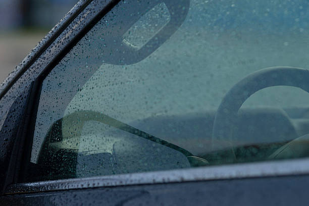istock Wet glass surface showing raindrops and blurred steering wheel silhouette 2246791827