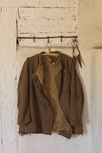 Old jacket on hanger and scissors hanging on a antique metal clothes rack on white painted wall, Jussarö, Raasepori, Finland.