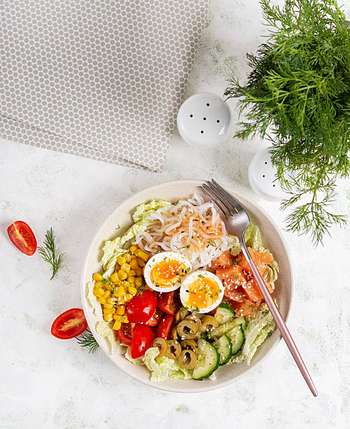 Buddha bowls of salmon, boiled egg, tomatoes, corn, cucumber, Shirataki noodles and sesame. Asian cuisine. Top view