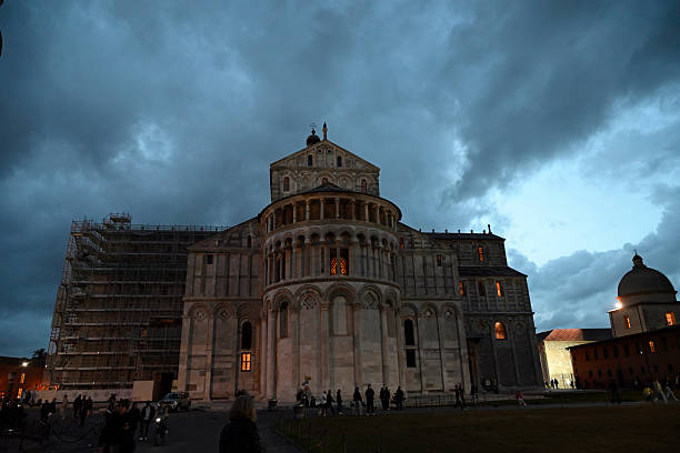 People around the Leaning Tower of Pisa. Marble tower with columns. Night scene. Sundown.