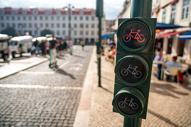 Cyclist and scooter passing through a red light on the bike path, Lisbon, Portugal.