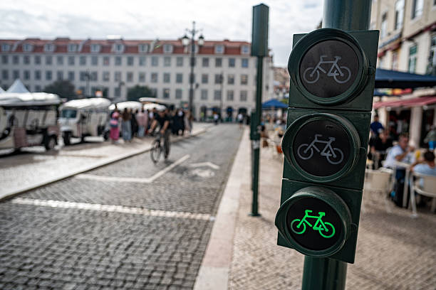 Cyclist and scooter passing through a green light on the bike path, Lisbon, Portugal.