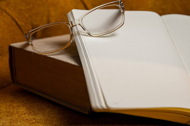 istock thick classic book, open blank notebook and a pair reading of glasses on mustard green sofa 2246805360