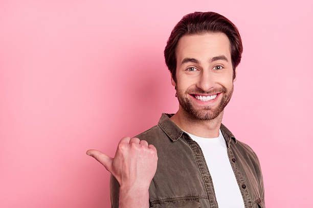 istock Photo of impressed pretty young guy dressed brown shirt pointing thumb empty space isolated pink color background 2246824092