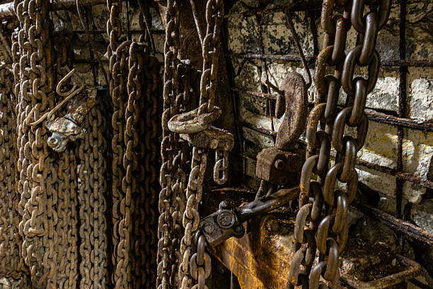 istock Heavy chains, hooks, air hoses, and cables on the floor of a dim coal mine. 2246828531