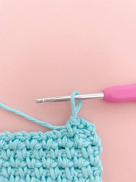 istock Close-Up of Blue Handmade Crochet Stitches with Hook on Pink Background 2246830396