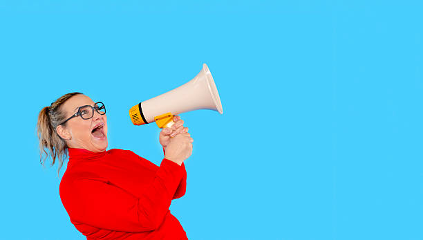 istock Excited woman shouting into a megaphone against a blue background 2246838370
