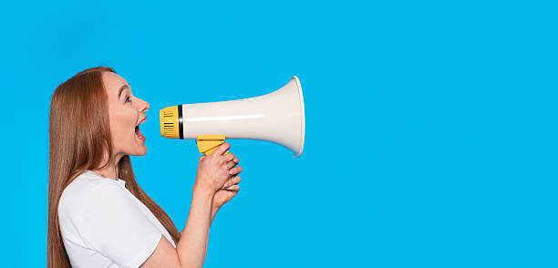 istock Woman using a megaphone to express ideas in front of a bright blue background 2246838620