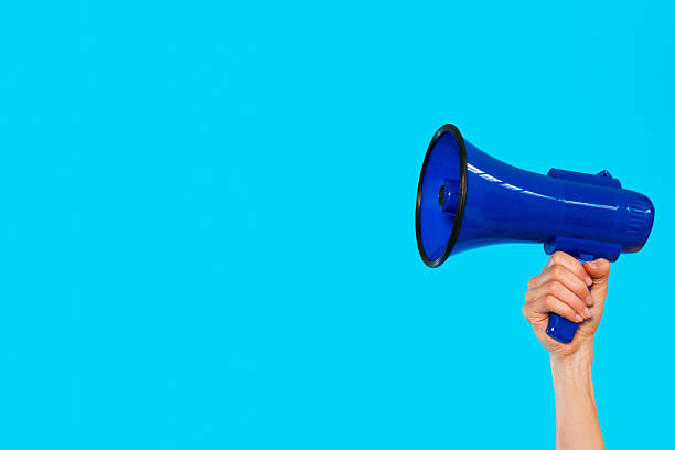 istock Hand holding a blue megaphone against a bright blue background 2246839674