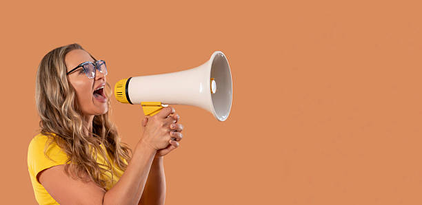 istock Woman using megaphone to convey a message in a warm-toned setting 2246840594