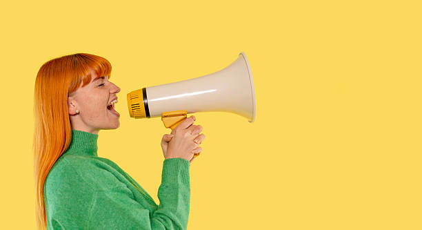 istock Person using a megaphone to communicate on a vibrant yellow background 2246841194