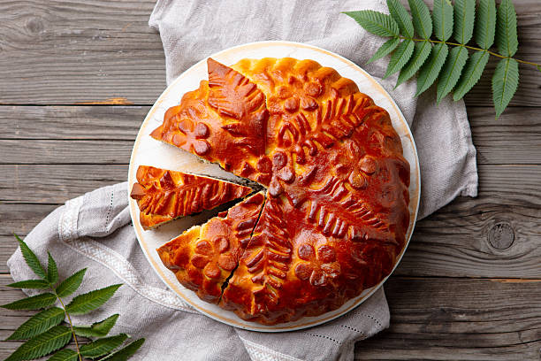 Pie with meat, potatoes and mushrooms on yeast dough. Traditional Russian kulebyaka. Wooden background and grey fabric. Close-up. View from above.