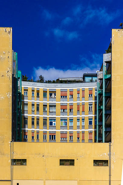 istock Curved Yellow Apartment Building With Bright Windows Against Deep Blue Sky 2246845831