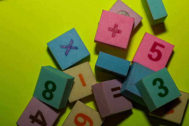 istock This photograph captures a random scatter of multi-colored blocks or tiles featuring embossed numbers and mathematical symbols on a vibrant lime-green background. 2246848066