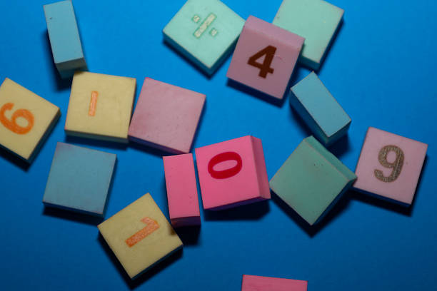 istock This close-up shot features a random scatter of multi-colored square tiles with embossed numbers and a mathematical symbol set against a bright blue background. 2246848074