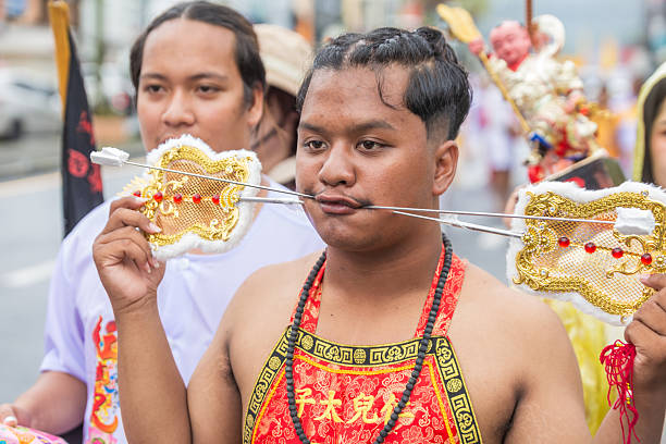 Phuket, Thailand - November 06 2025: A devoted participant in the Phuket Vegetarian Festival (Nine Emperor Gods Festival) with ritualistic cheek piercing, demonstrating intense spiritual