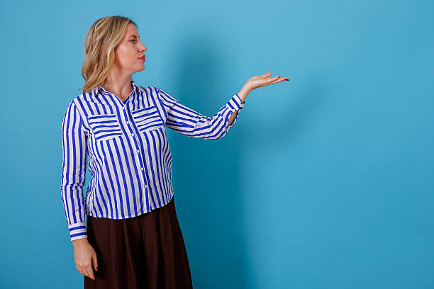 istock Woman presenting and demonstrating with empty palm standing against blue background, offering copy space 2246852713