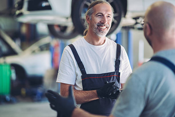 istock Smiling auto mechanics discussing work in the garage 2246854855