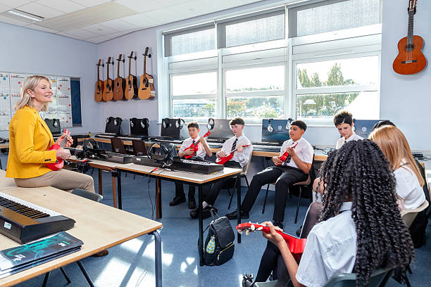 istock Secondary school class holding ukuleles, watching the teacher in a music lesson 2246856248