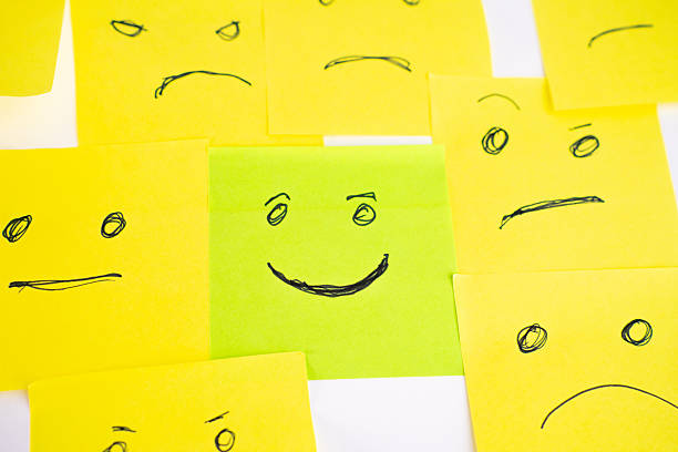 istock Happy green face surrounded by Angry and sad yellow post-it faces 2246859376