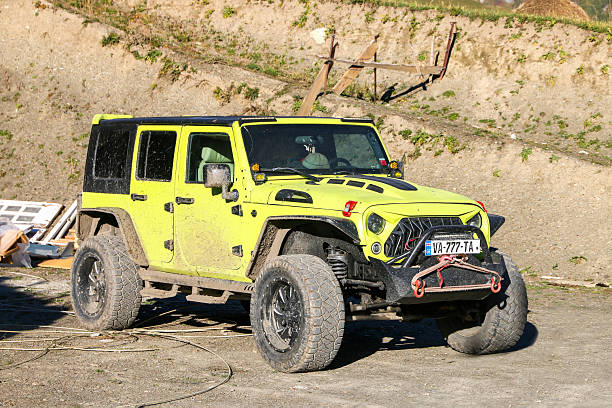 Ushguli, Georgia - September 24, 2025: Yellow offroad car Jeep Wrangler Unlimited (JK) in the town street.